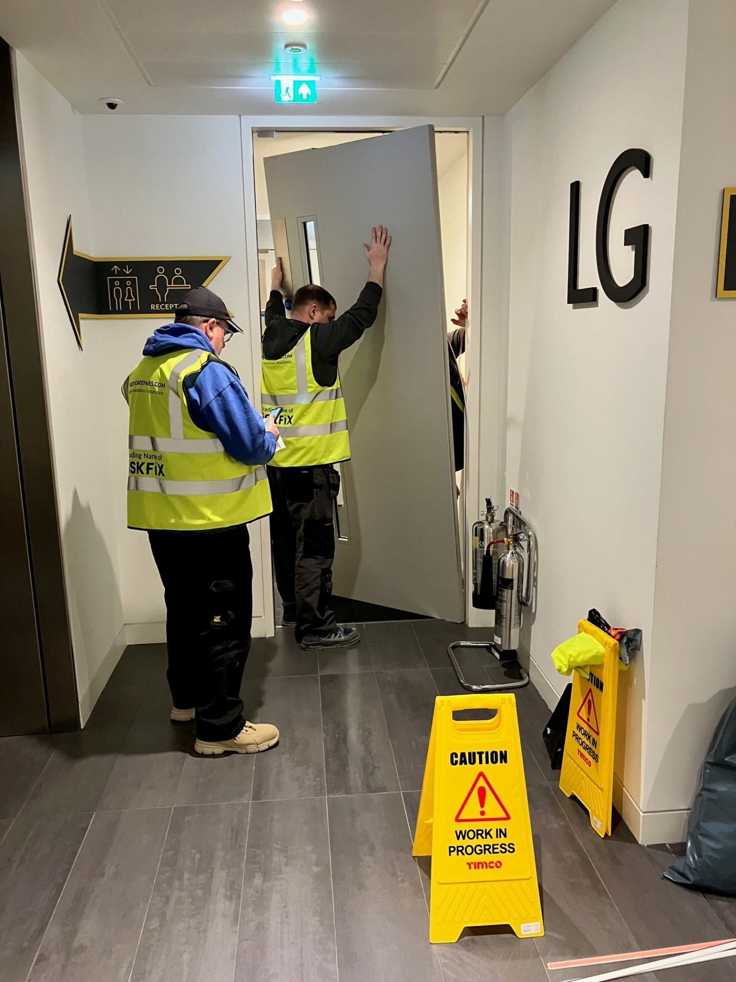 Fire door installers fitting a certified FD-rated doorset in a commercial building