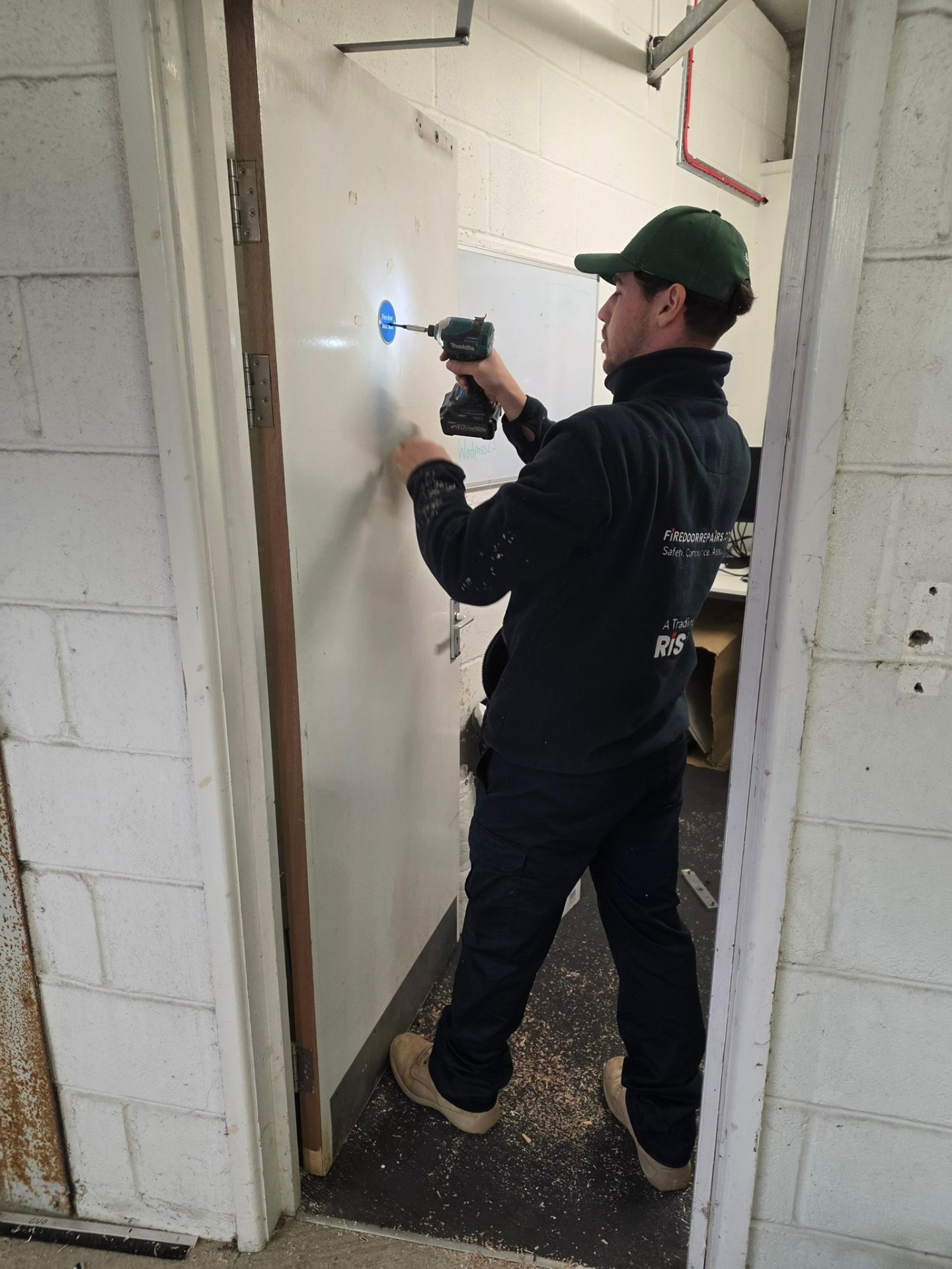 Technician carrying out fire door repair work on site in Suffolk